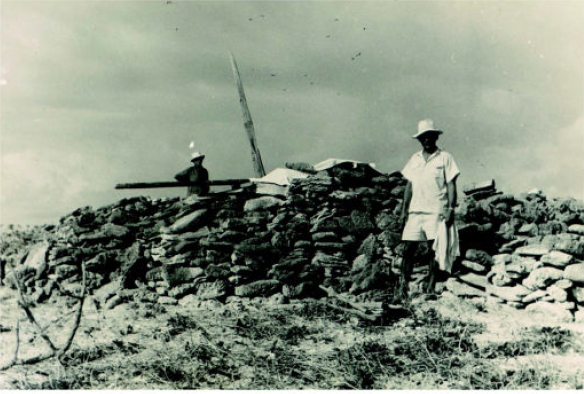 Workers installing the weather station on Tromelin Island pose beside castaways' ruins